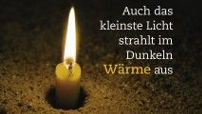 Das Bild zeigt eine brennende Kerze mit einer deutschen Adventsbotschaft.
