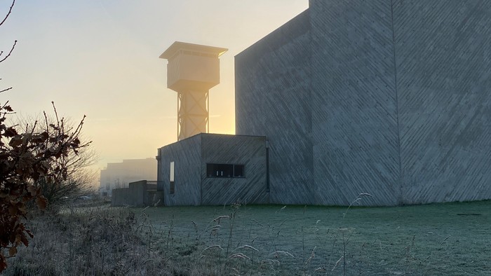 En frostklar morgen med solopgang foran en grå kirkebygning og kirketårn.