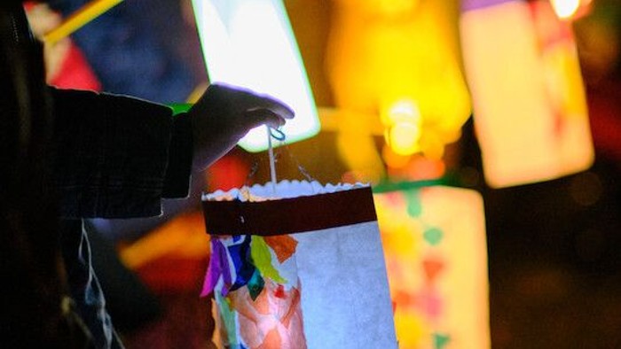 Bunte Laternen erleuchten eine festliche Abendszene im Freien mit unscharfen Figuren im Hintergrund.
