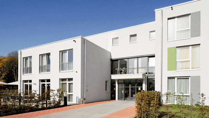 Modernes Wohngebäude mit großen Fenstern und grünem Akzent in der Fassade