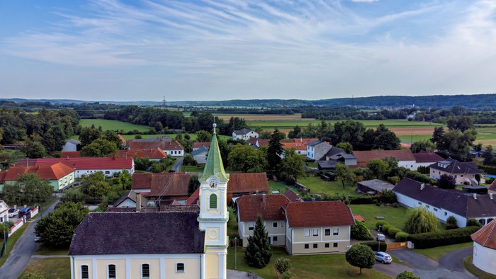 Luftaufnahme einer kleinen Stadt mit einer markanten Kirche und umliegender Landschaft
