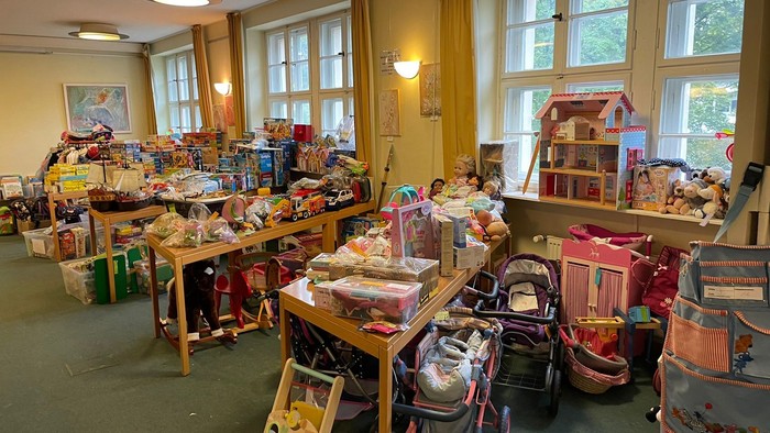 Viele Spielzeuge und Kinderwagen in einem Raum mit großen Fenstern