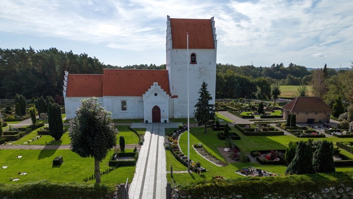 Luftfoto af en fredelig kirke og et velholdt kirkegård med en central sti, der fører til indgangen.