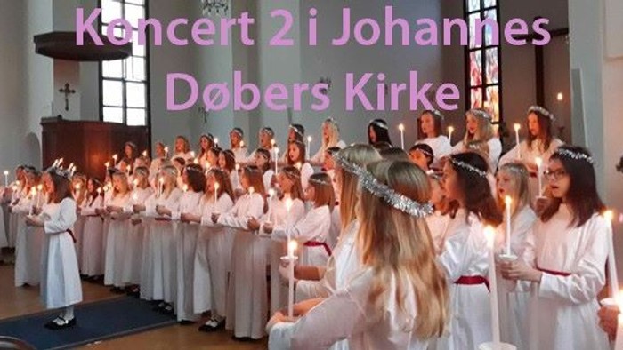 En gruppe børn i hvide tøjer med lysstaker ved koncert i kirke
