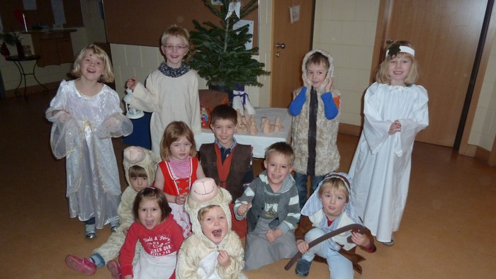 Kinder in Weihnachtskostümen posieren vor Christbaum