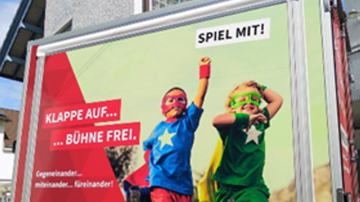 Kinder spielen auf LKW-Werbung, Haus im Hintergrund