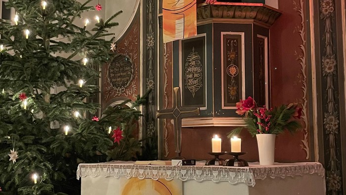 Weihnachtsdekoration in Kirche mit Christbaum und Krippenbild