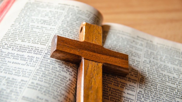 Ein aufgeschlagener Bibel mit einem Holzkreuz