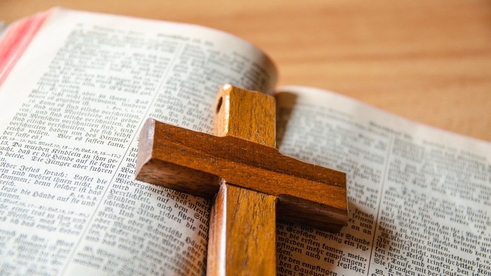 Ein aufgeschlagener Bibel mit einem Holzkreuz