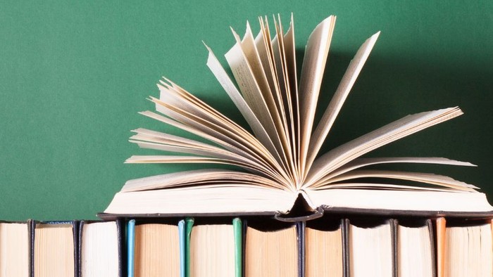 Bücher in einer Reihe, darauf ein aufgeschlagenes Buch