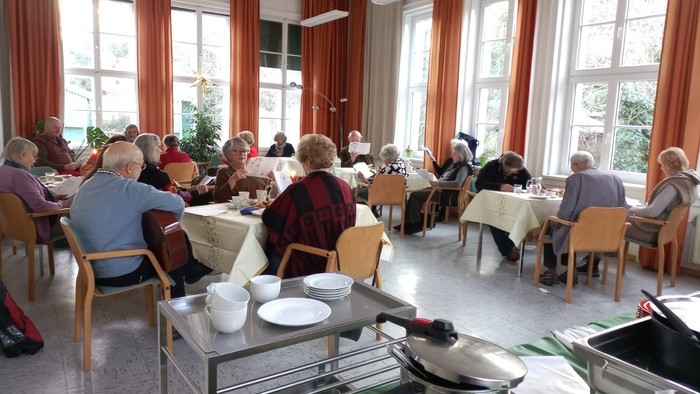 Senioren essen in einem hellen Speisesaal mit großen Fenstern.
