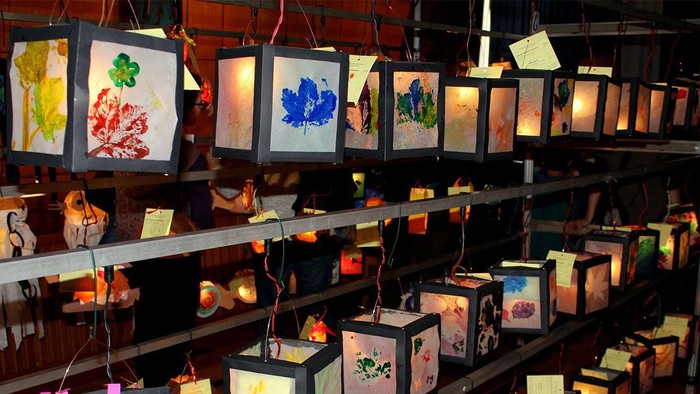 Viele bunte Laternen hängen in Regalen, einige mit Blumenmustern.