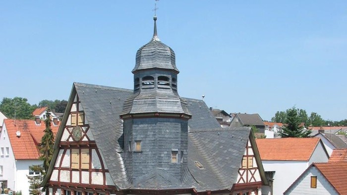 Ein malerisches Fachwerkhaus mit einem markanten Turm in einem idyllischen europäischen Dorf.
