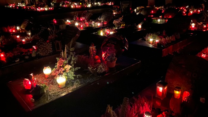 Viele brennende Kerzen auf Gräbern in der Nacht