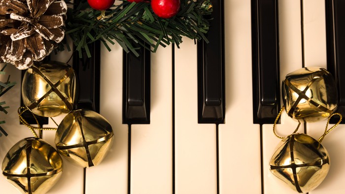 Gulde juleglokker på piano-taster med grønne grane og røde bær