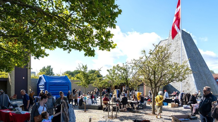 En gruppe af mennesker er samlet på en plads med en stor pyramide og et flag.