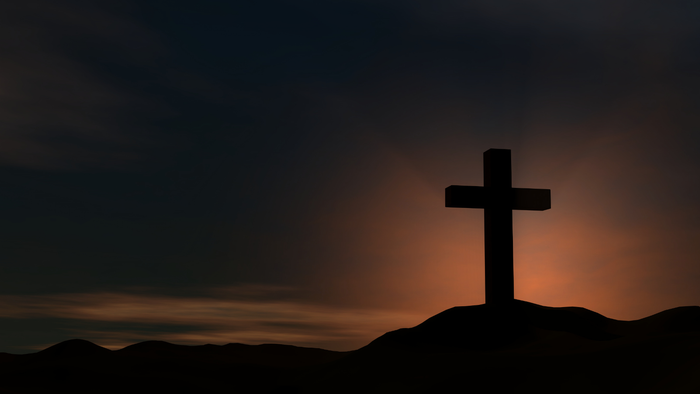 Ein Kreuz vor Sonnenuntergang auf einem Berg.