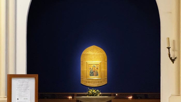 Elegante Kapelle mit goldenem Altarnischen-Interieur, das religiöse Kunstwerke zeigt, umgeben von Kirchenbänken und Kerzenhaltern.