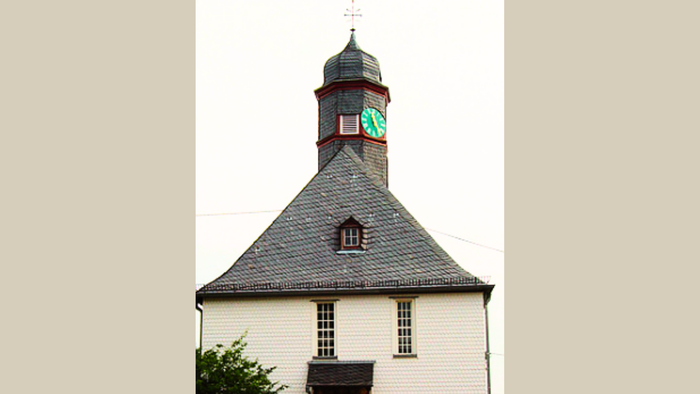 Weißes Kirchlein mit Uhrturm und spitzem Dach
