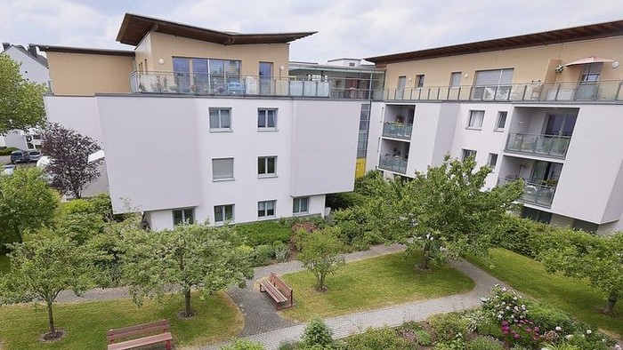 Moderner Wohnkomplex-Innenhof mit angelegter Gartenanlage, Bänken und kleinen Bäumen.