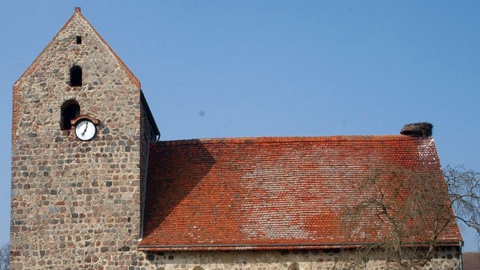 Alte Kirche mit Turm und Zifferblatt unter blauem Himmel