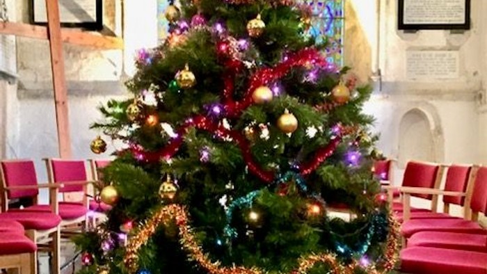 Christmas tree decorated with colorful ornaments and lights in a church setting