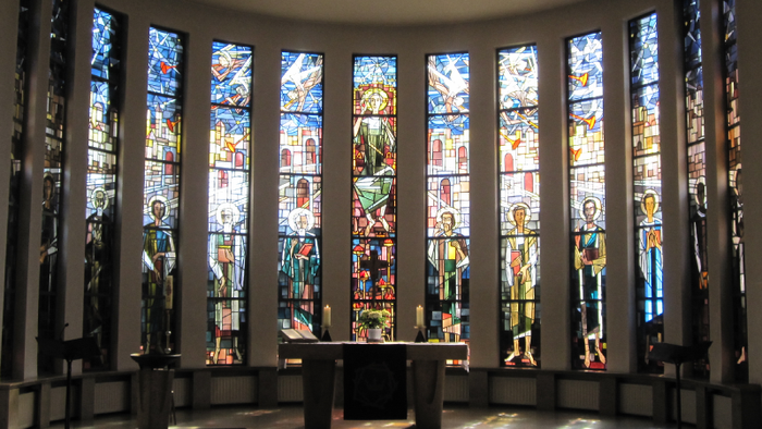 Farbenfrohe Kirchenfenster mit religiösen Motiven erhellen den Innenraum