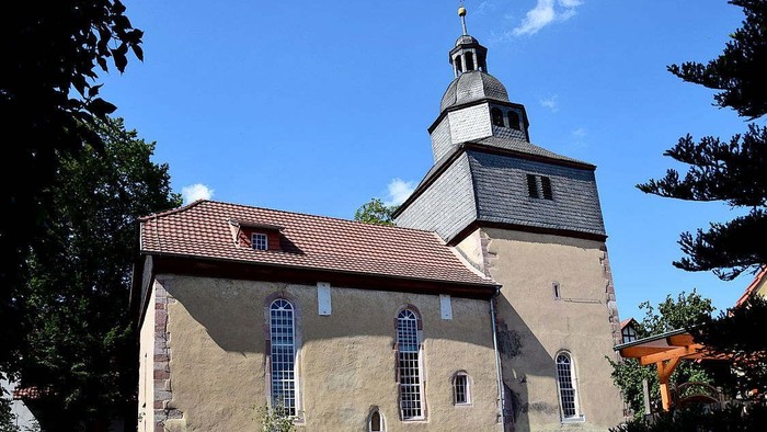 Kirchengebäude mit hohem Turm und rotem Dach unter blauem Himmel