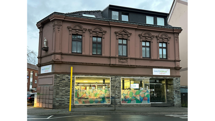 Das Bild zeigt ein mehrstöckiges Gebäude mit einem Geschäft im Erdgeschoss.