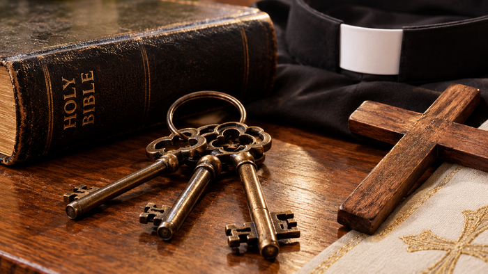 A wooden table with a Bible, Priest's collar, wooden cross, and set of keys, on top of it.