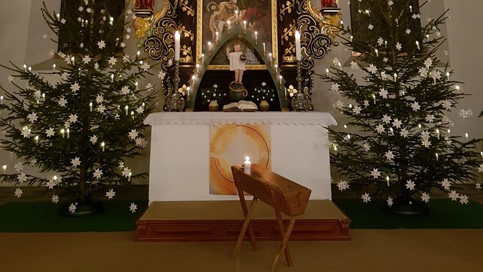 Weihnachtsdekoration in der Kirche mit Krippenszene und Tannenbäumen