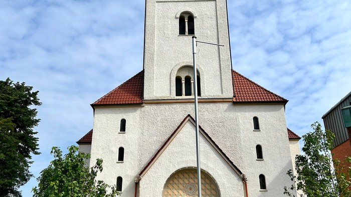 Weiße Kirche mit hohem Glockenturm und rotem Dach.