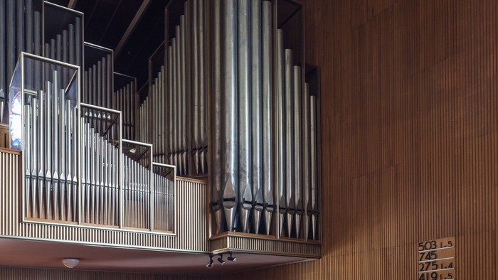 Große Kirchenorgel aus Holz mit mehreren Registern und Tasten, über dem Eingang.