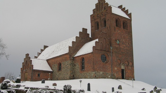 En snede kirke med teglmur og spisse tårne.