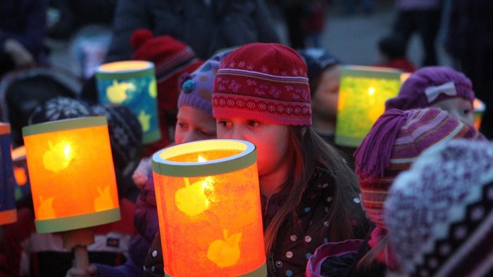 Kinder mit leuchtenden Laternen, die Wintermützen und Schals tragen.