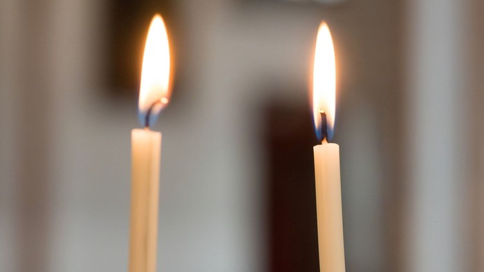 Zwei brennende Kerzen vor unscharfem Hintergrund