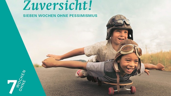 Das Buchcover zeigt zwei Kinder in Flugzeugen, die auf einer Straße liegen und lachen.