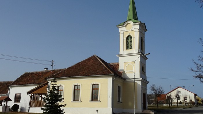 Kleine Kirche mit hohem Turm und grünem Dach in ländlicher Gegend