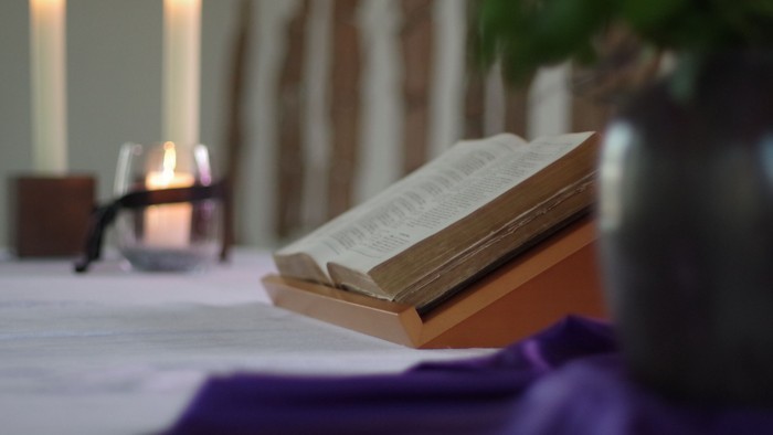 Offene Bibel auf Tisch mit Kerzen und Blumen