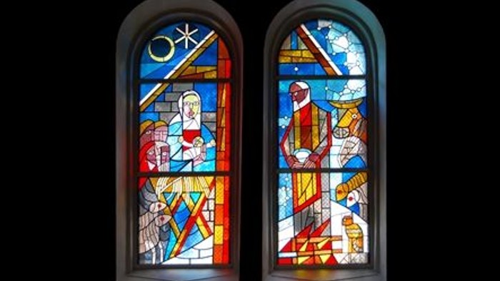 Buntglasfenster mit biblischen Szenen der Kreuzigung und Auferstehung in lebendigen, farbenfrohen Motiven.