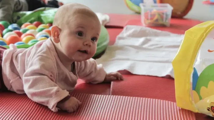 Baby auf roter Matte mit Spielzeug.