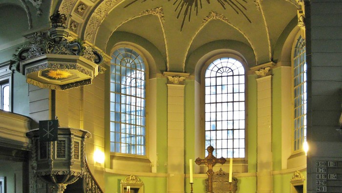 Innenraum einer Kirche mit Altarraum und Deckenverzierungen