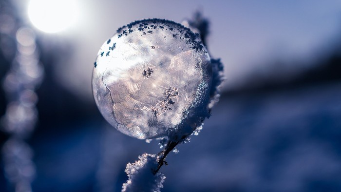 Frostklædt kugle, der glitrer med indviklede iskristaller mod en vinterlig baggrund.
