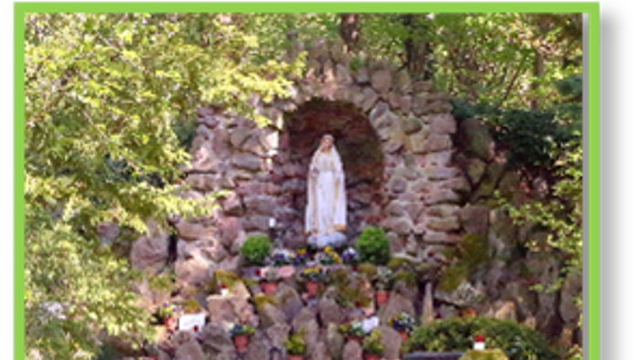 Ein friedvoller Gartenschrein zeigt eine Statue der Jungfrau Maria, umgeben von leuchtenden Blumen und üppigem Grün.