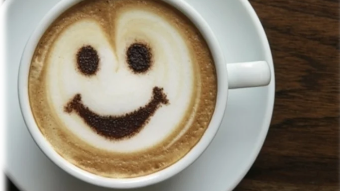 En kaffe med et smilende ansigt lavet af skum på overfladen.