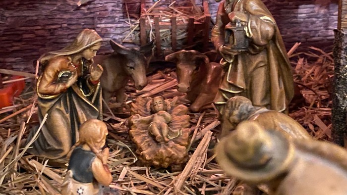 Eine Krippe mit Figuren, die die Geburt Jesu darstellen, mit Maria, Josef, dem Kind in der Krippe, Tieren und einem Engel.
