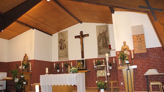 Elegante Kircheninnenausstattung mit einem Altar, der mit religiösen Statuen, Kerzen und einem Kruzifix geschmückt ist.