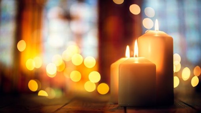 Zwei brennende Kerzen vor Weihnachtsbeleuchtung