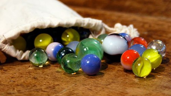 Bunte Murmeln in einem Stoffbeutel auf Holzboden