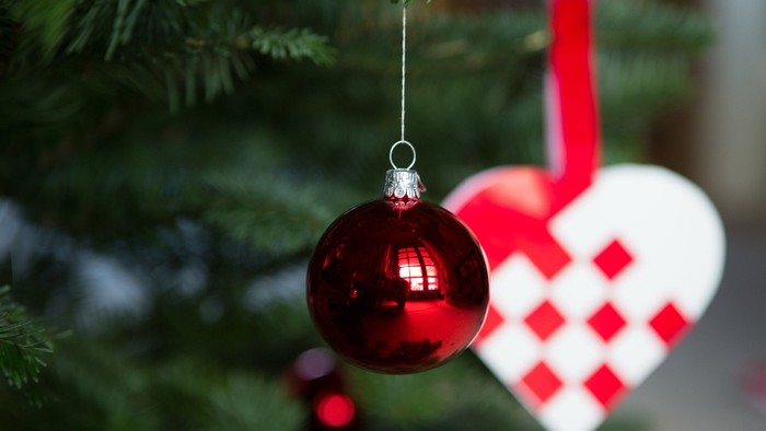 En rød glaskugle hænger på en jul ejendommeligt med en hjerteformet pynt.